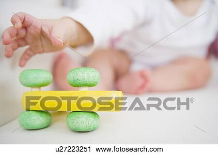Stock Image - Baby boy (6-11 months) reaching for toy. Fotosearch