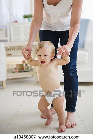 Baby boy (6-11 months) walking with mother View Large Photo Image Stock Photo - Baby boy (6-11 months) walking with mother. Fotosearch