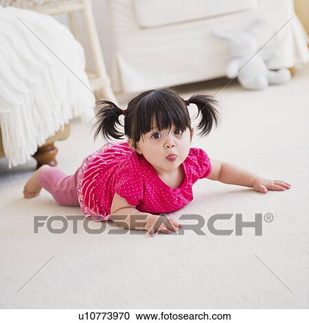 Stock Image - Baby girl (12-17 months) crawling on carpet. Fotosearch