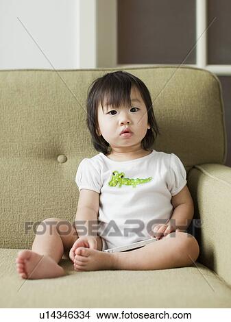 Picture - Baby girl (12-17 months) on sofa. Fotosearch