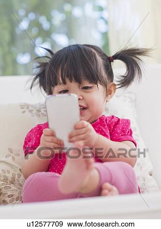 Baby girl (12-17 months) playing with mobile phone View Large Photo Image Stock Photo - Baby girl (12-17 months) playing with mobile phone. Fotosearch