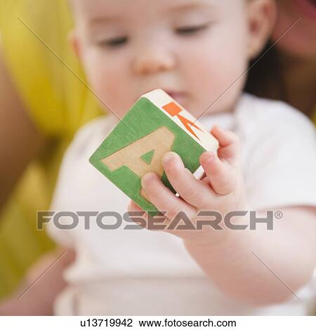 Baby girl (6-11 months) holding block View Large Photo Image Stock Image - Baby girl (6-11 months) holding block. Fotosearch