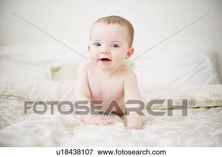 Stock Photo - Baby girl (6-11 months) lying on bed. Fotosearch