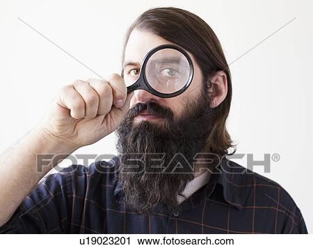 Bearded young man looking through magnifying glass View Large Photo Image Stock Image - Bearded young man looking through magnifying glass. Fotosearch