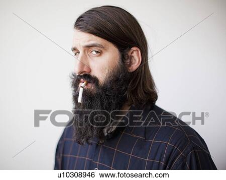 Stock Photograph - Bearded young man with broken cigarette in his mouth. Fotosearch