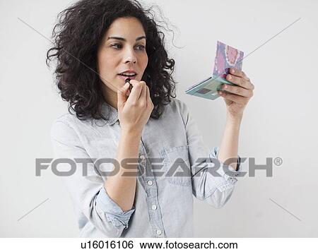 Stock Photograph - Beautiful young woman applying lipstick. Fotosearch