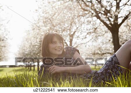 Stock Image - Belgium, Sint-Truiden, Portrait of young woman in spring orchard. Fotosearch