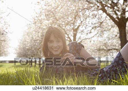 Stock Image - Belgium, Sint-Truiden, Portrait of young woman in spring orchard. Fotosearch