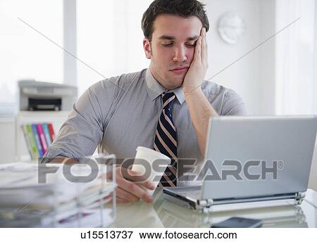 Bored business man working on laptop View Large Photo Image Stock Photo - Bored business man working on laptop. Fotosearch