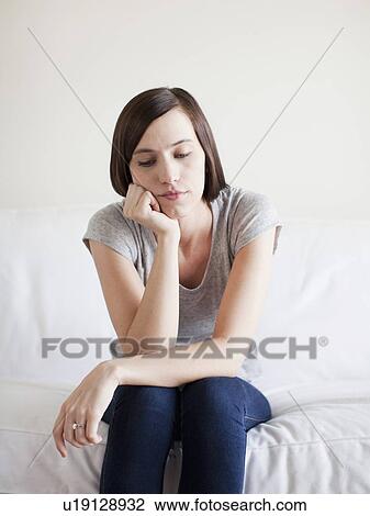 Bored young woman sitting on bed View Large Photo Image Stock Image - Bored young woman sitting on bed. Fotosearch