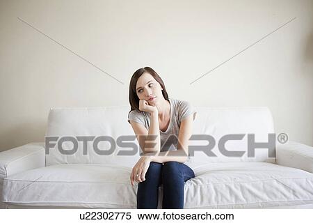 Stock Photography - Bored young woman sitting on bed. Fotosearch