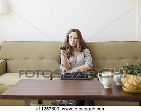 Bored young woman sitting on sofa with remote control View Large Photo Image Stock Photo - Bored young woman sitting on sofa with remote control. Fotosearch