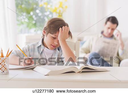 Boy (10-11 years) doing homework at table with father sitting in background View Large Photo Image Stock Image - Boy (10-11 years) doing homework at table with father sitting in background. Fotosearch