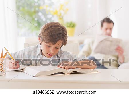 Boy (10-11 years) doing homework at table with father sitting in background View Large Photo Image Stock Image - Boy (10-11 years) doing homework at table with father sitting in background. Fotosearch