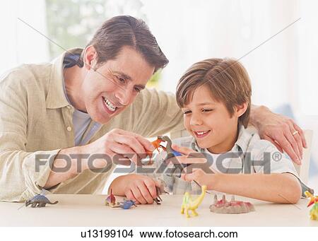 Boy (10-11 years) playing with father with toy dinosaurs View Large Photo Image Picture - Boy (10-11 years) playing with father with toy dinosaurs. Fotosearch
