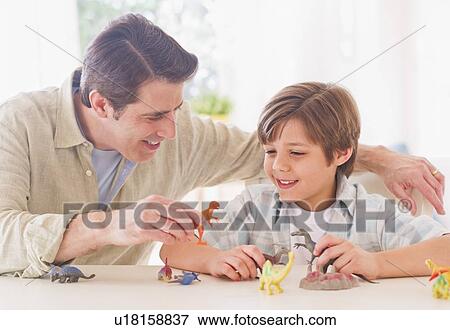 Boy (10-11 years) playing with father with toy dinosaurs View Large Photo Image Stock Photo - Boy (10-11 years) playing with father with toy dinosaurs. Fotosearch