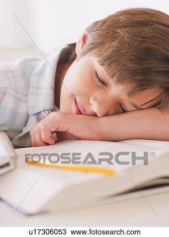 Stock Image - Boy (10-11 years) sleeping on books while doing homework. Fotosearch
