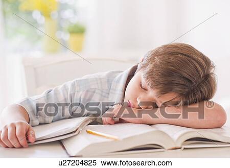 Stock Photography - Boy (10-11 years) sleeping on books while doing homework. Fotosearch