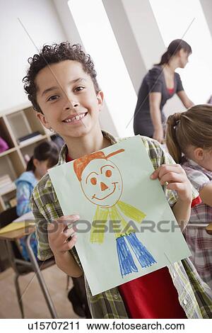 Stock Image - Boy (8-9) showing his drawing. Fotosearch