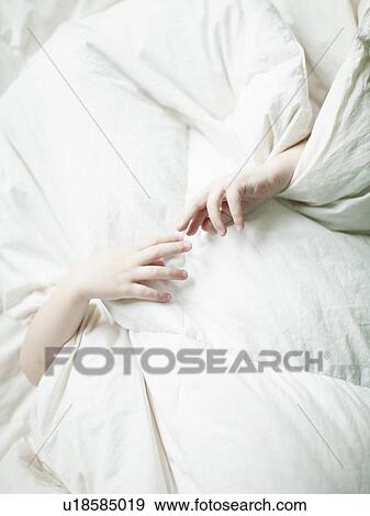 Stock Photo - Boys hands (2-3) sticking out from under quilt. Fotosearch