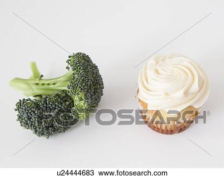 Stock Image - Broccoli and muffin on white background, studio shot. Fotosearch