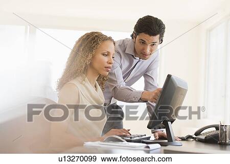 Stock Photo - Business man and woman looking at computer. Fotosearch