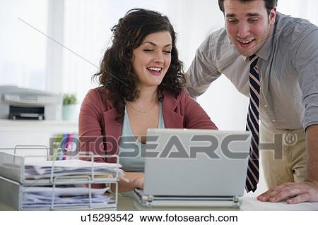 Stock Image - Business woman and business man working on laptop. Fotosearch
