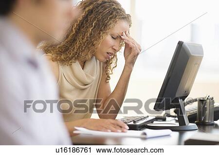 Stock Image - Business woman having headache in office. Fotosearch