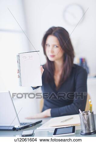 Picture - Businesswoman at desk showing to do list. Fotosearch