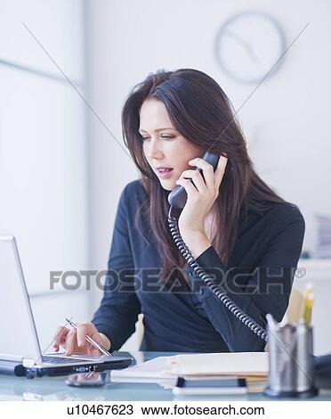 Stock Image - Businesswoman working at desk. Fotosearch