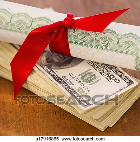 Stock Photography - Close up of diploma and banknotes, studio shot. Fotosearch