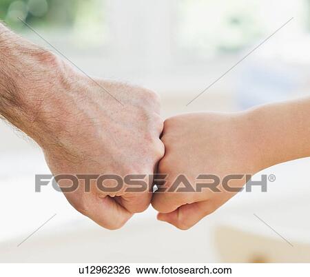 Stock Photograph - Close up of father's and son's (10-11 years) hands doing fist bump. Fotosearch
