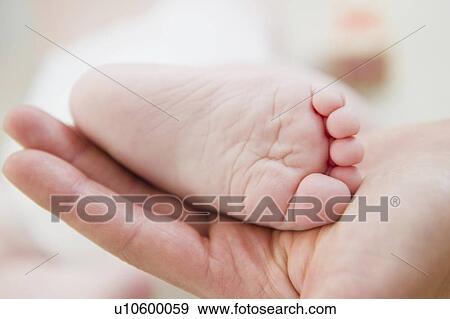 Close up of mother's hand holding baby daughter's (6-11 months) foot View Large Photo Image Stock Photo - Close up of mother's hand holding baby daughter's (6-11 months) foot. Fotosearch