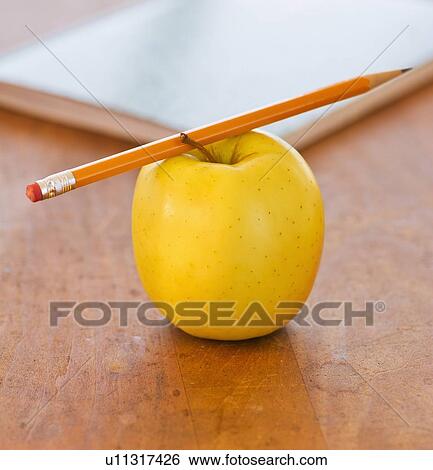 Stock Photograph -  Close up of pencil on apple, studio shot. Fotosearch