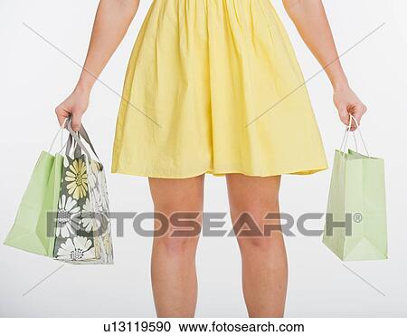 Stock Image - Close up of woman carrying shopping bags, studio shot. Fotosearch