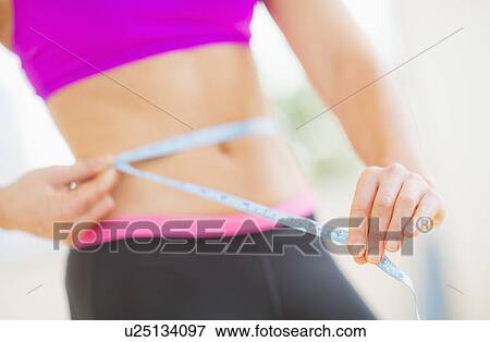Close up of woman measuring herself with tape measure View Large Photo Image Stock Photo - Close up of woman measuring herself with tape measure. Fotosearch