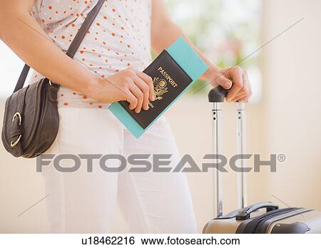 Stock Photograph - Close up of woman with luggage and passport. Fotosearch