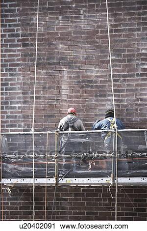 Stock Image - Construction workers on scaffolding. Fotosearch