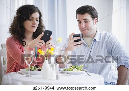 Couple having dinner and text messaging View Large Photo Image Picture - Couple having dinner and text messaging . Fotosearch