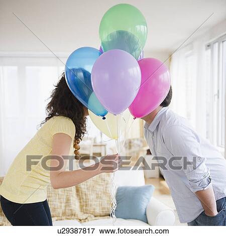 Couple kissing behind bunch of colorful balloons View Large Photo Image Stock Photo - Couple kissing behind bunch of colorful balloons. Fotosearch