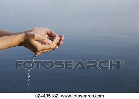 Stock Image - Cupped hands holding water from lake. Fotosearch