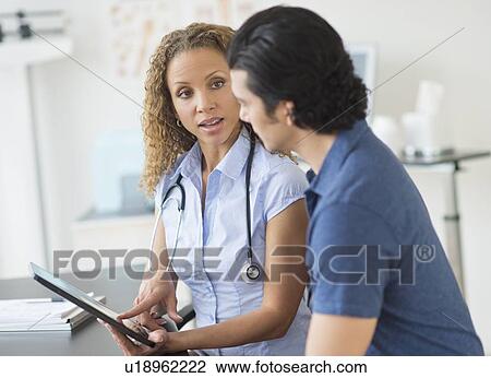 Doctor and patient talking in clinic using tablet pc View Large Photo Image Stock Image - Doctor and patient talking in clinic using tablet pc. Fotosearch