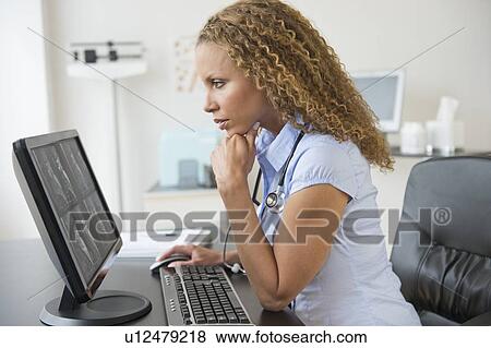 Doctor looking at computer View Large Photo Image Stock Photo - Doctor looking at computer. Fotosearch