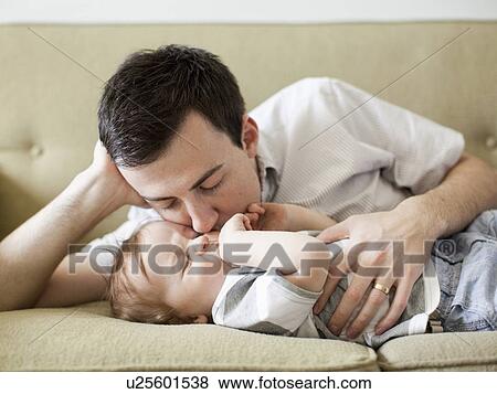 Father and baby boy (6-11 months) lying on sofa View Large Photo Image Stock Photo - Father and baby boy (6-11 months) lying on sofa. Fotosearch
