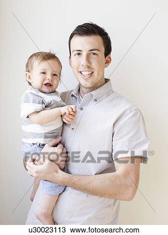 Stock Image - Father and baby boy (6-11 months) posing for portrait. Fotosearch