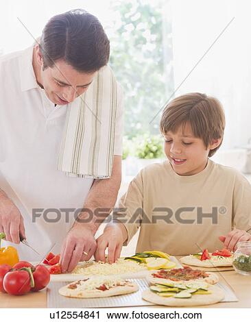 Stock Image - Father and son (10-11 years) preparing pizza. Fotosearch
