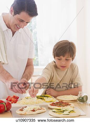 Stock Photography - Father and son (10-11 years) preparing pizza. Fotosearch