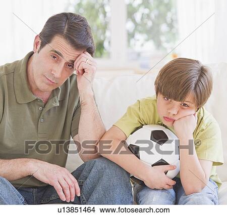 Father and son (10-11 years) watching football match with sadness View Large Photo Image Picture - Father and son (10-11 years) watching football match with sadness. Fotosearch