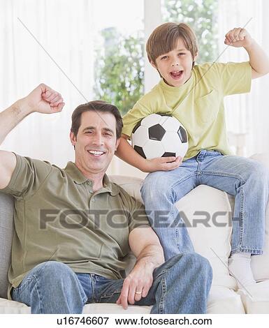 Stock Photo - Father and son (10-11 years) watching football match with excitement. Fotosearch