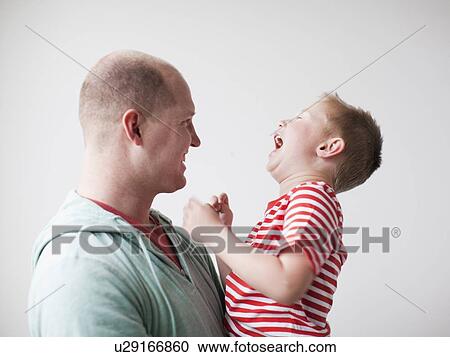 Stock Image - Father and toddler boy (2-3) embracing. Fotosearch